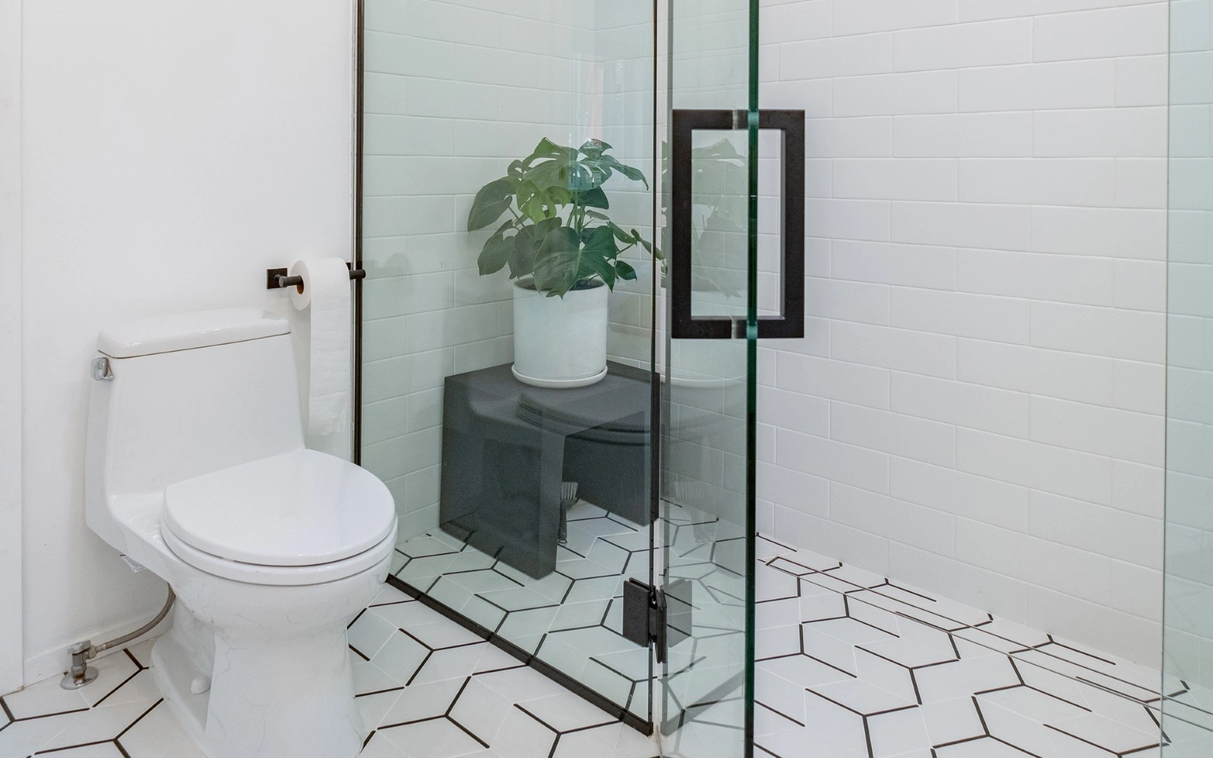 Curbless walk-in shower in a Los Angeles ADU with frameless glass, black hardware, a linear drain, and geometric floor tile