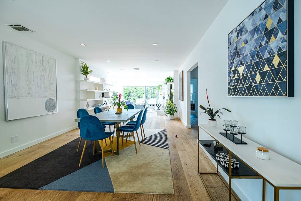 Open dining and living area in a Los Angeles ADU with wide-plank oak floors, built-in shelving, and sliding doors to the patio