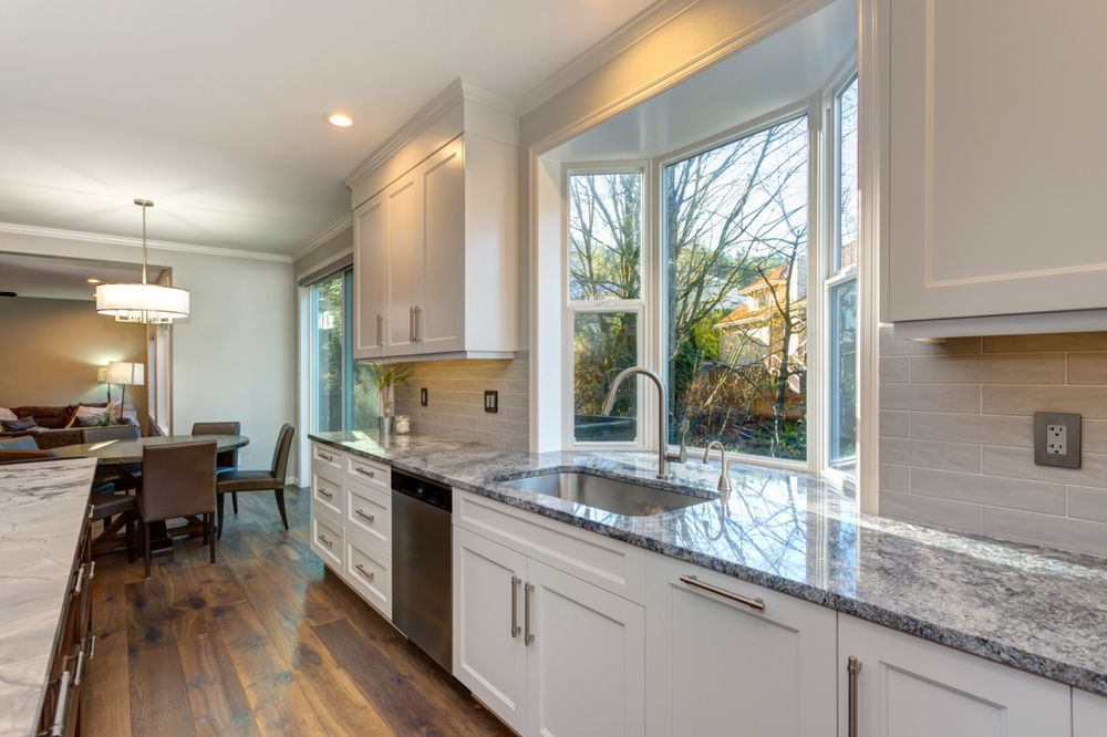 Kitchen with white shaker cabinets, gray granite countertops, an undermount sink under a bay window, and a gray subway tile backsplash