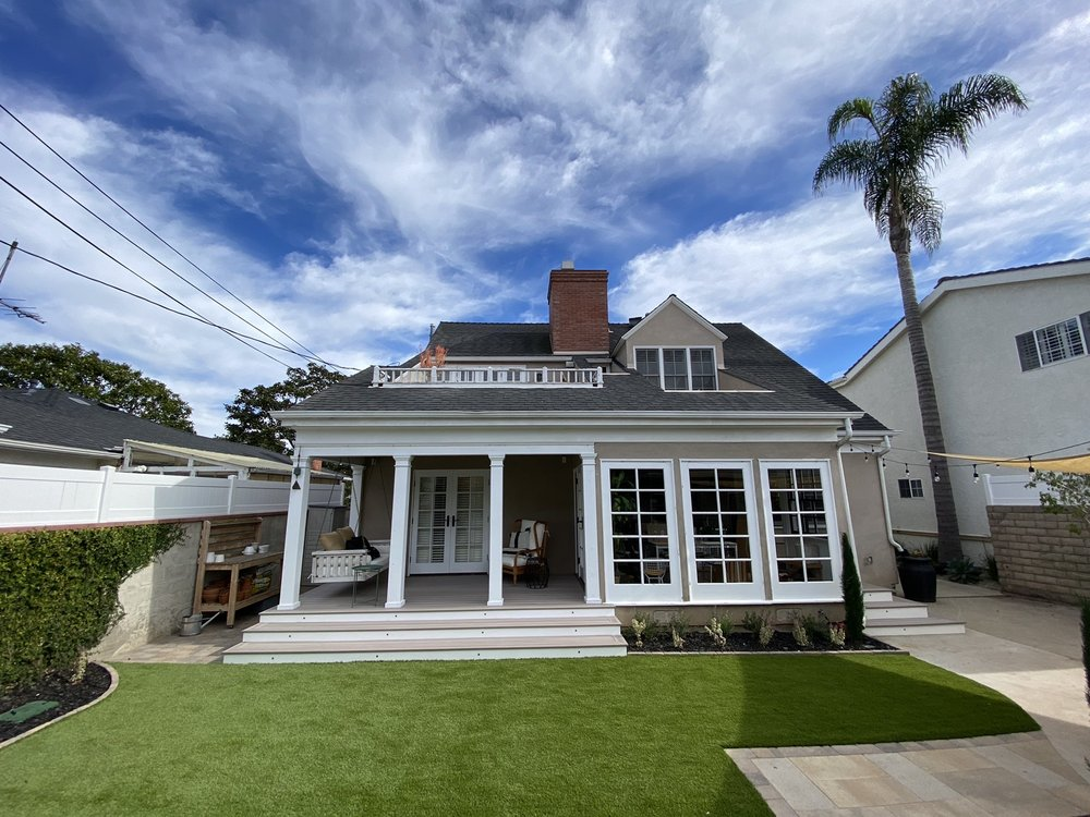 Covered back porch deck in Los Angeles with white columns, wide wraparound steps, and a rooftop balcony railing above