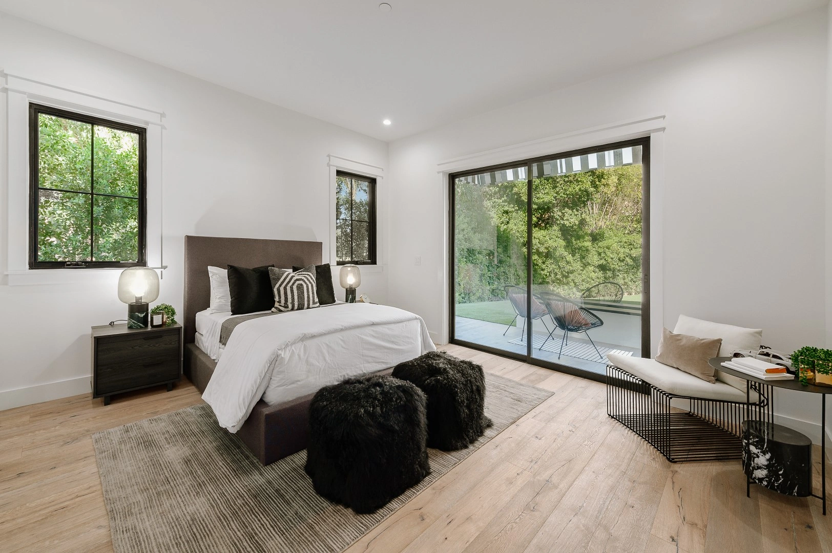 Bedroom in a Los Angeles ADU with black-framed windows and a sliding glass door opening to a backyard patio
