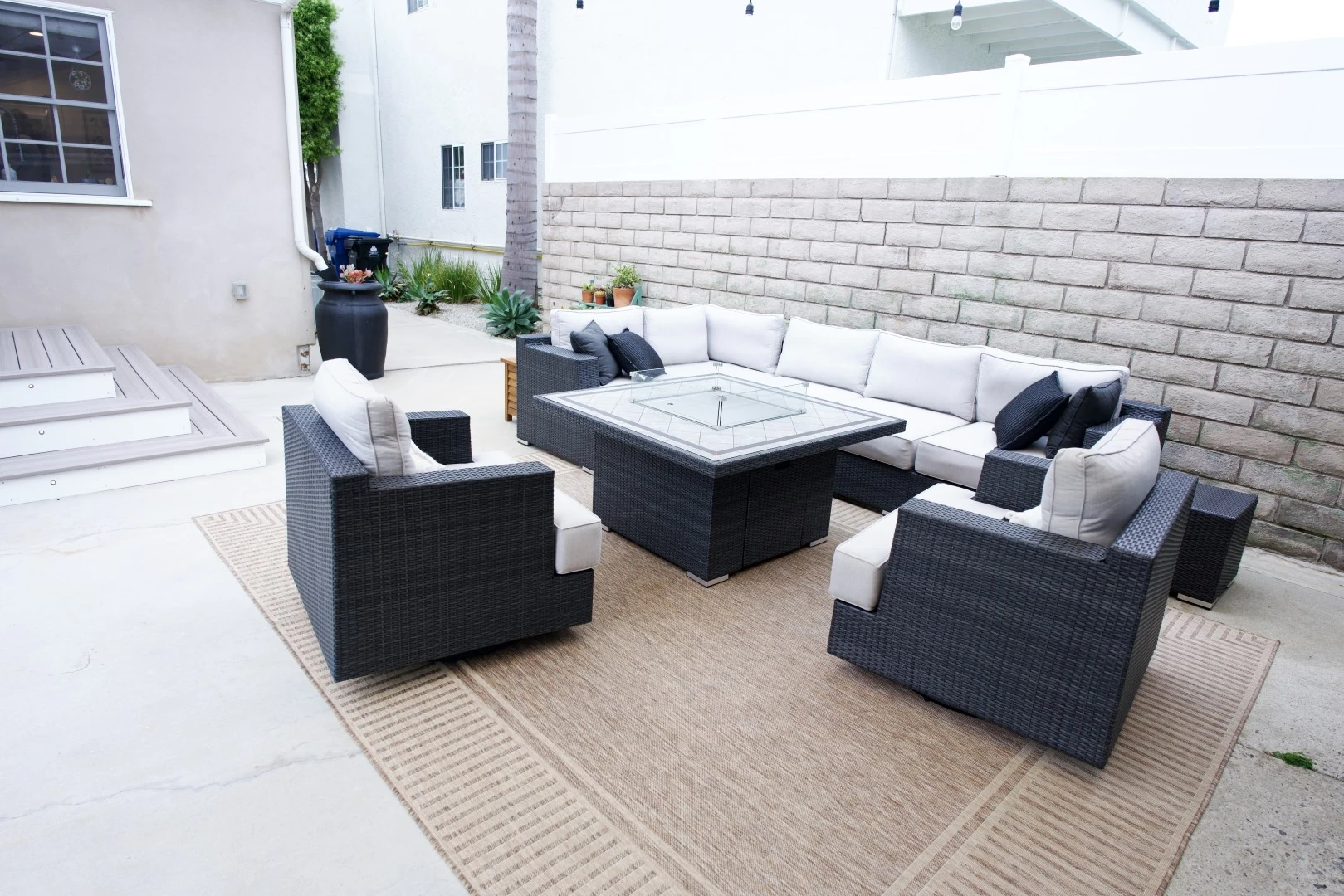 Wraparound composite deck steps with white risers and built-in step lights leading to a backyard patio in Los Angeles