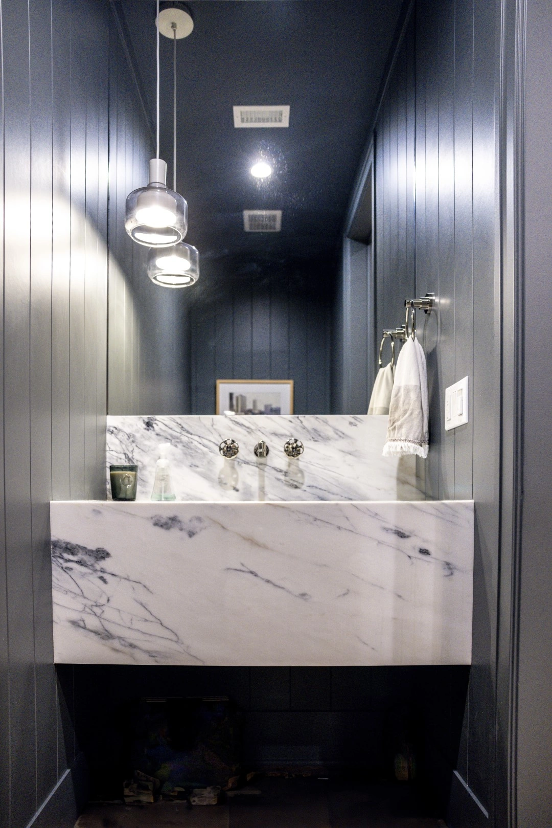 Powder room remodel in Los Angeles with a floating marble vanity, wall-mounted faucet, and navy paneled walls