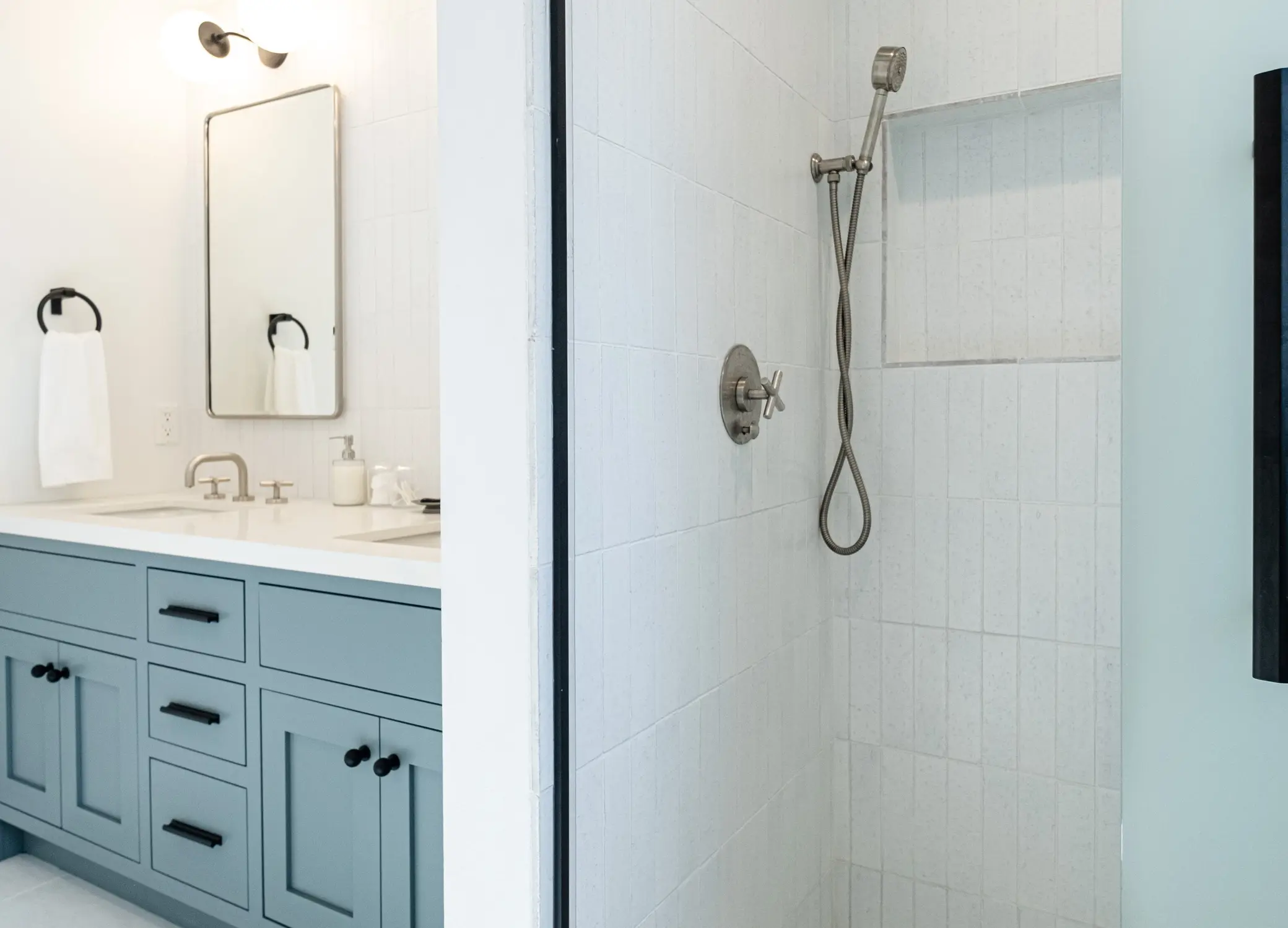 Bathroom remodel in Los Angeles with a teal vanity and adjoining tiled shower