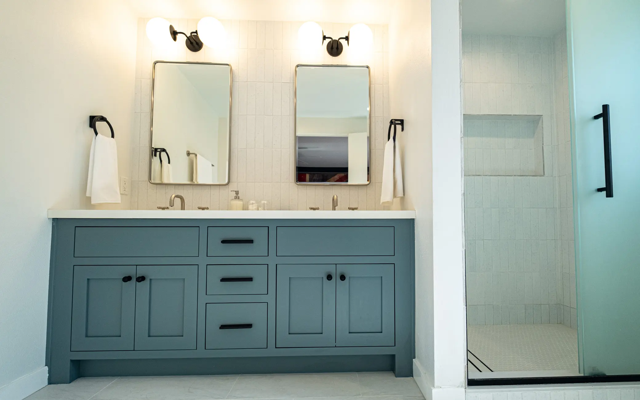 Bathroom remodel in Los Angeles with a teal vanity and glass-enclosed shower