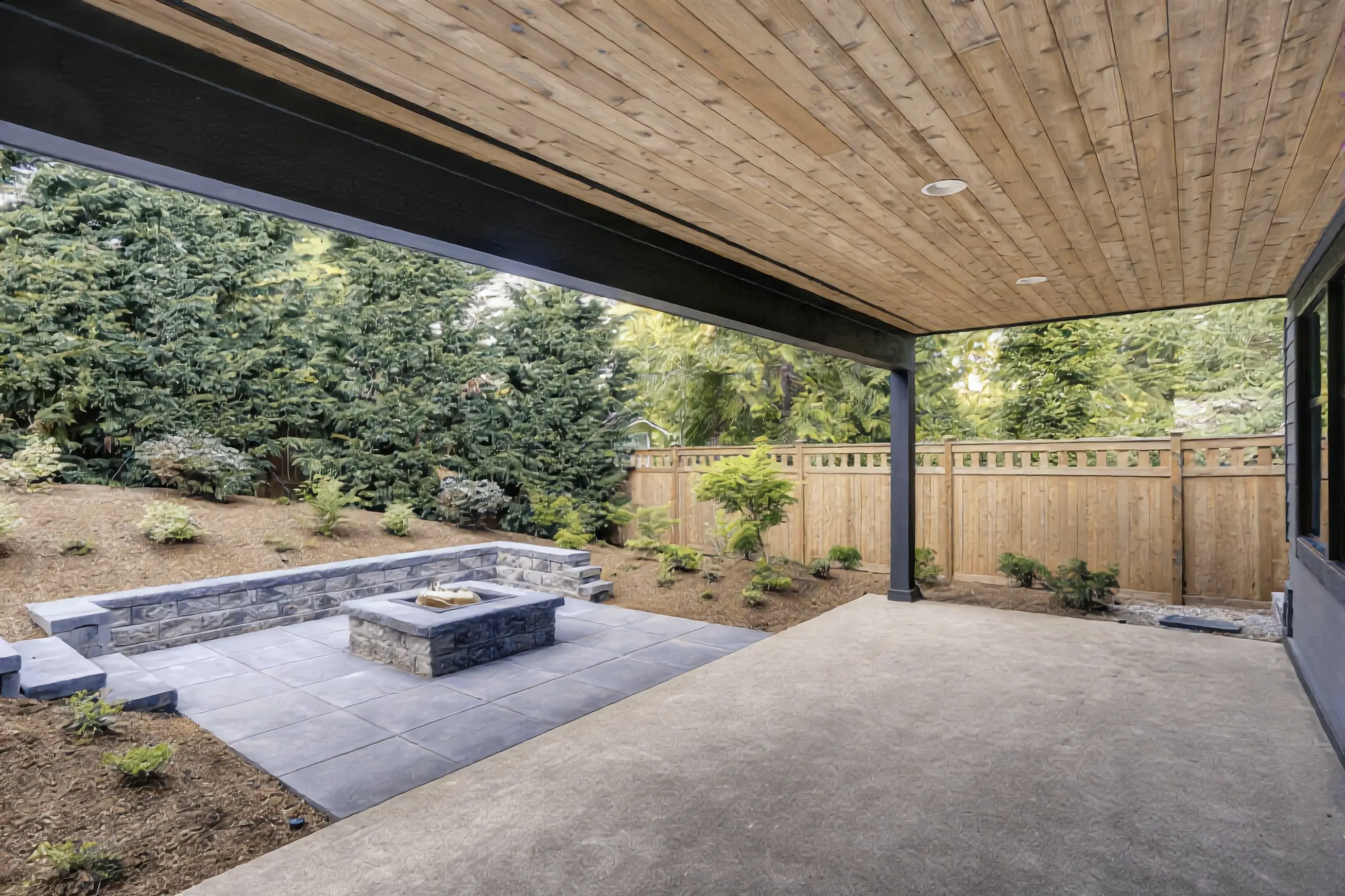 Paver patio with stone fire pit and seat wall beside a covered patio in Los Angeles