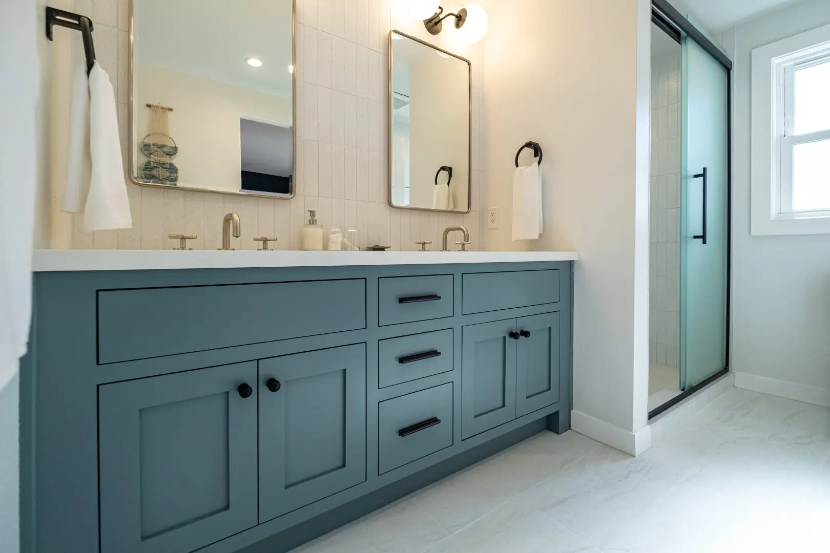 Blue-gray shaker double vanity with rounded mirrors and black towel rings in a Burbank bathroom remodel