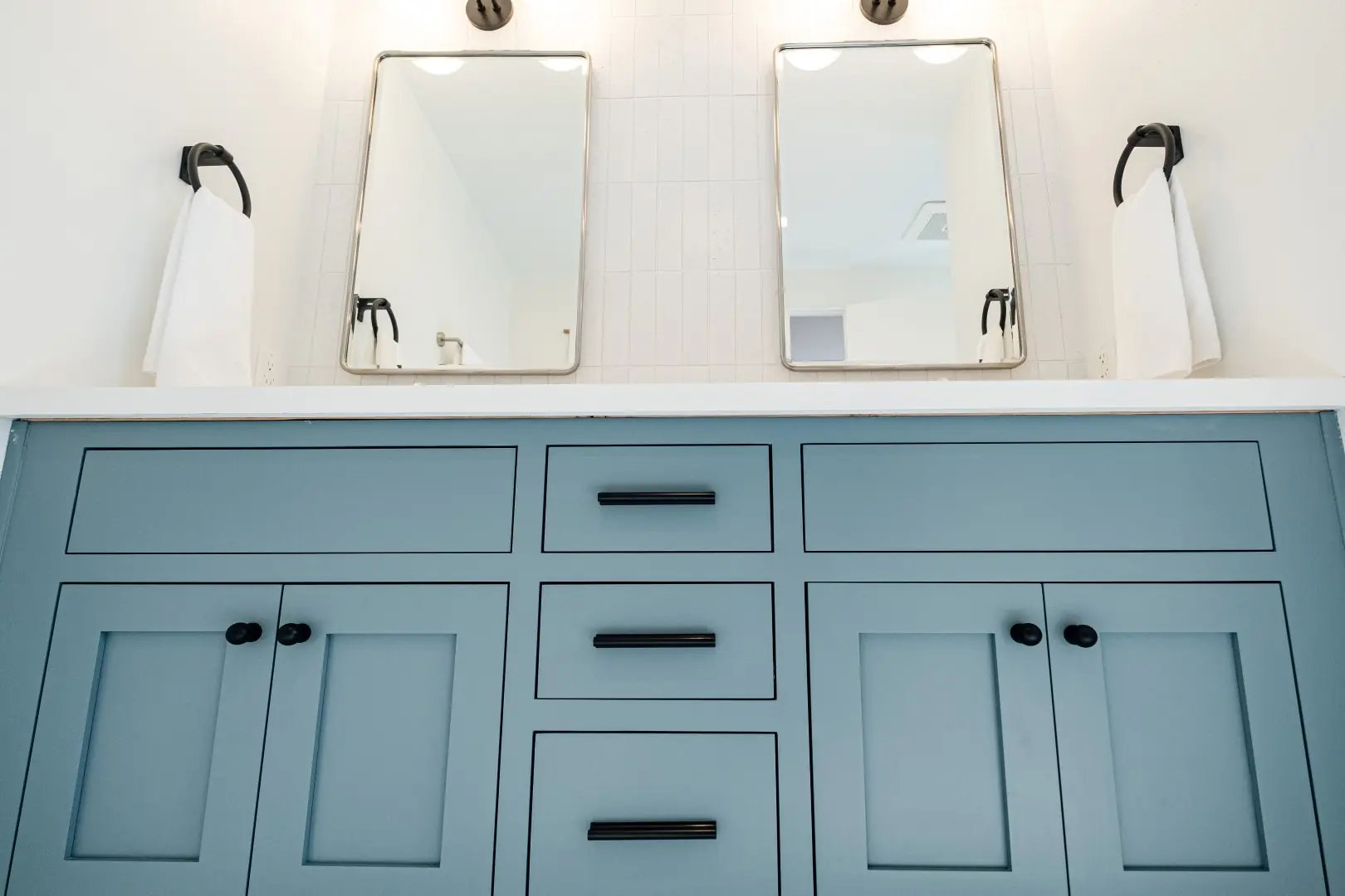 Blue-gray inset vanity with black pulls and rounded mirrors in a Burbank bathroom remodel