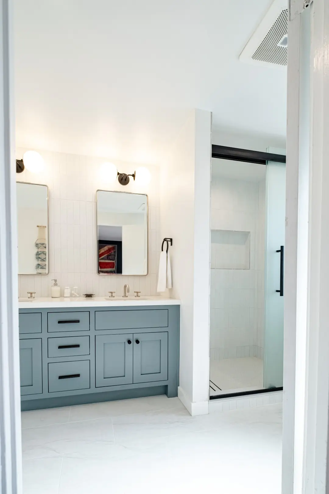 Doorway view of a Burbank bathroom remodel with a blue-gray vanity and a walk-in shower with a niche