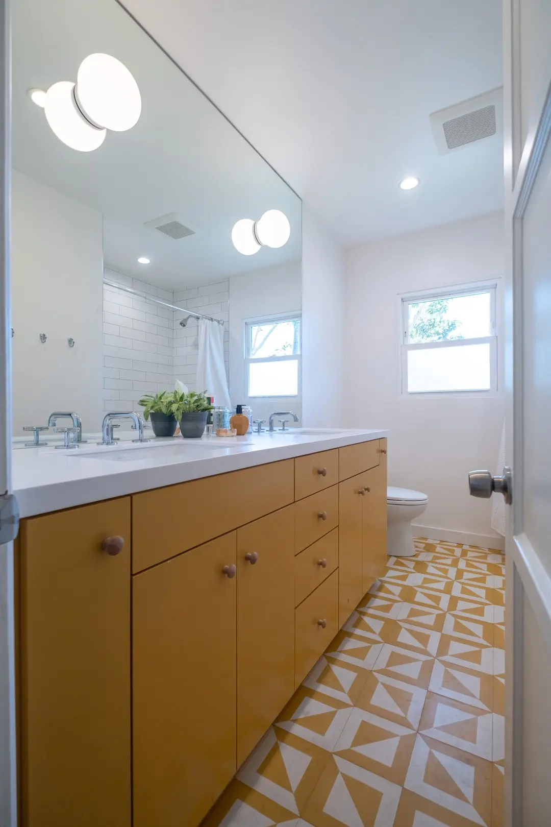 Bathroom with a wood double vanity and yellow patterned floor tile in a Santa Monica remodel