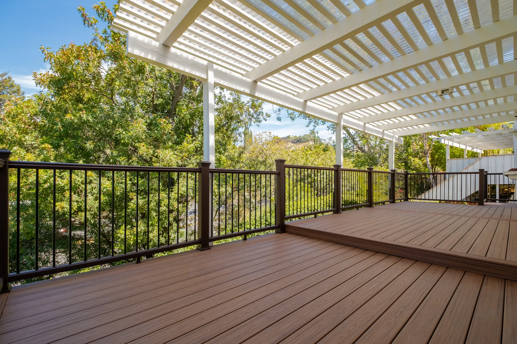 Custom composite deck with white slatted patio cover and black railings in Beverly Glen, Los Angeles