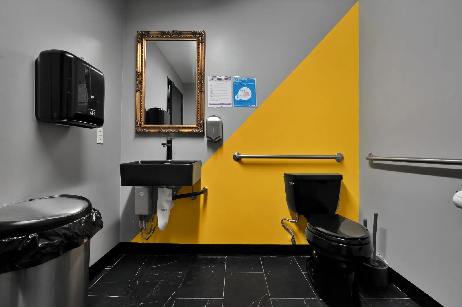 Cleopatra Tattoo accessible restroom with a yellow accent wall, black fixtures, and grab bars in Santa Monica