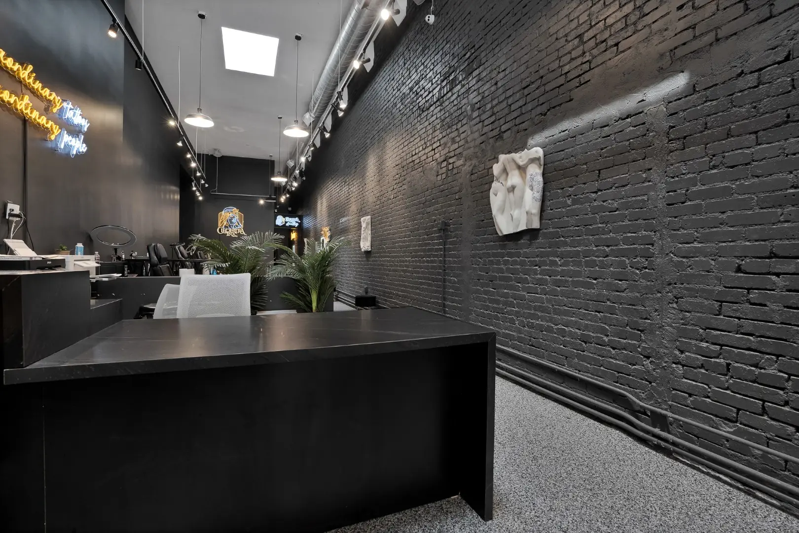 Cleopatra Tattoo desk and painted brick wall under track lighting and skylights in Santa Monica