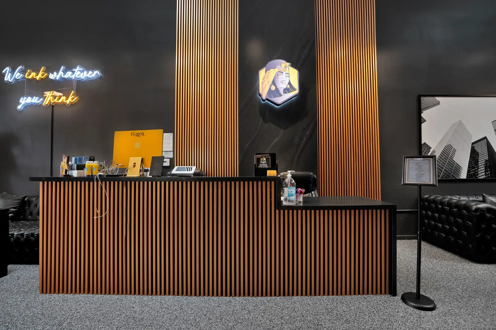Cleopatra Tattoo reception desk wrapped in wood slat millwork with matching slat columns and a neon sign in Santa Monica