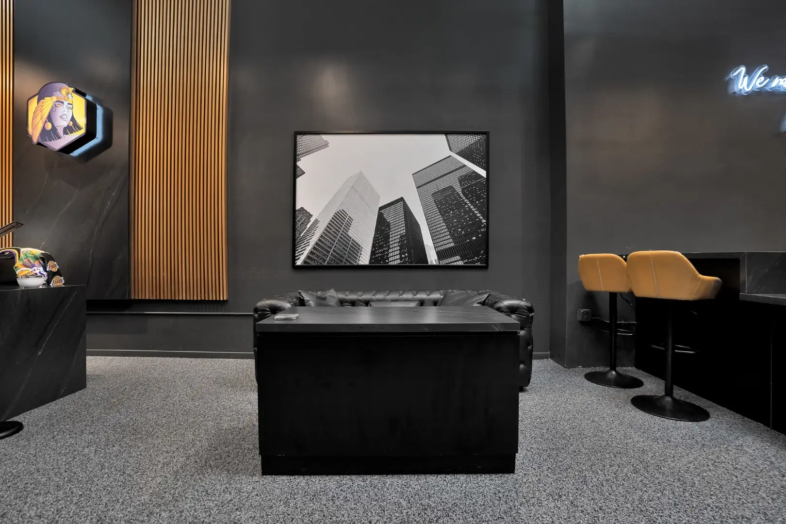 Cleopatra Tattoo waiting area with a leather sofa, black desk, and wood slat column in Santa Monica