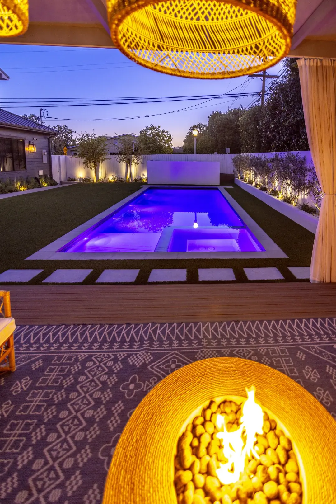 Sheens Project LED-lit pool and spa seen from the cabana lounge with a fire pit at night in Los Angeles