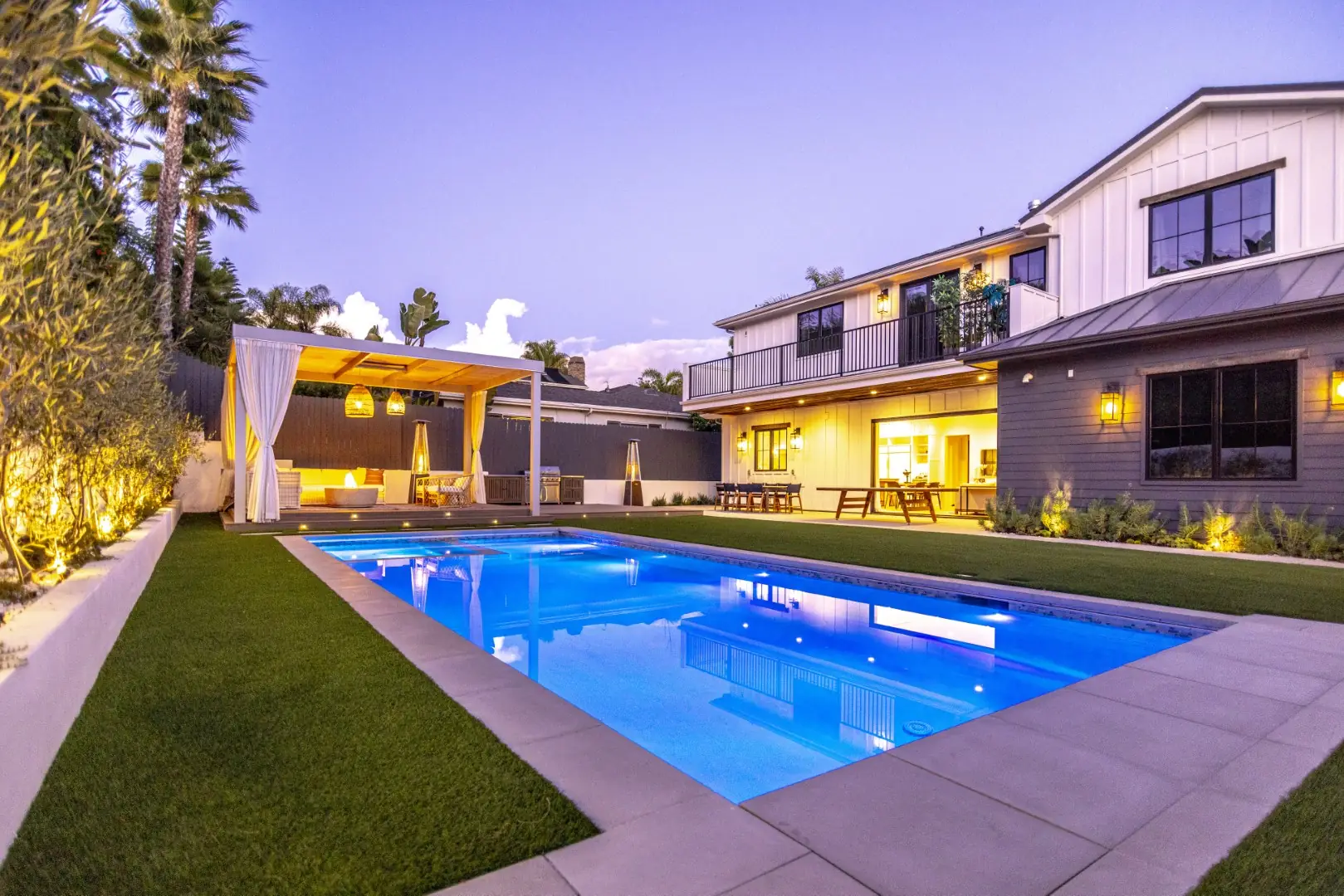 Sheens Project rectangular pool at dusk reflecting the modern farmhouse and curtained cabana in Los Angeles