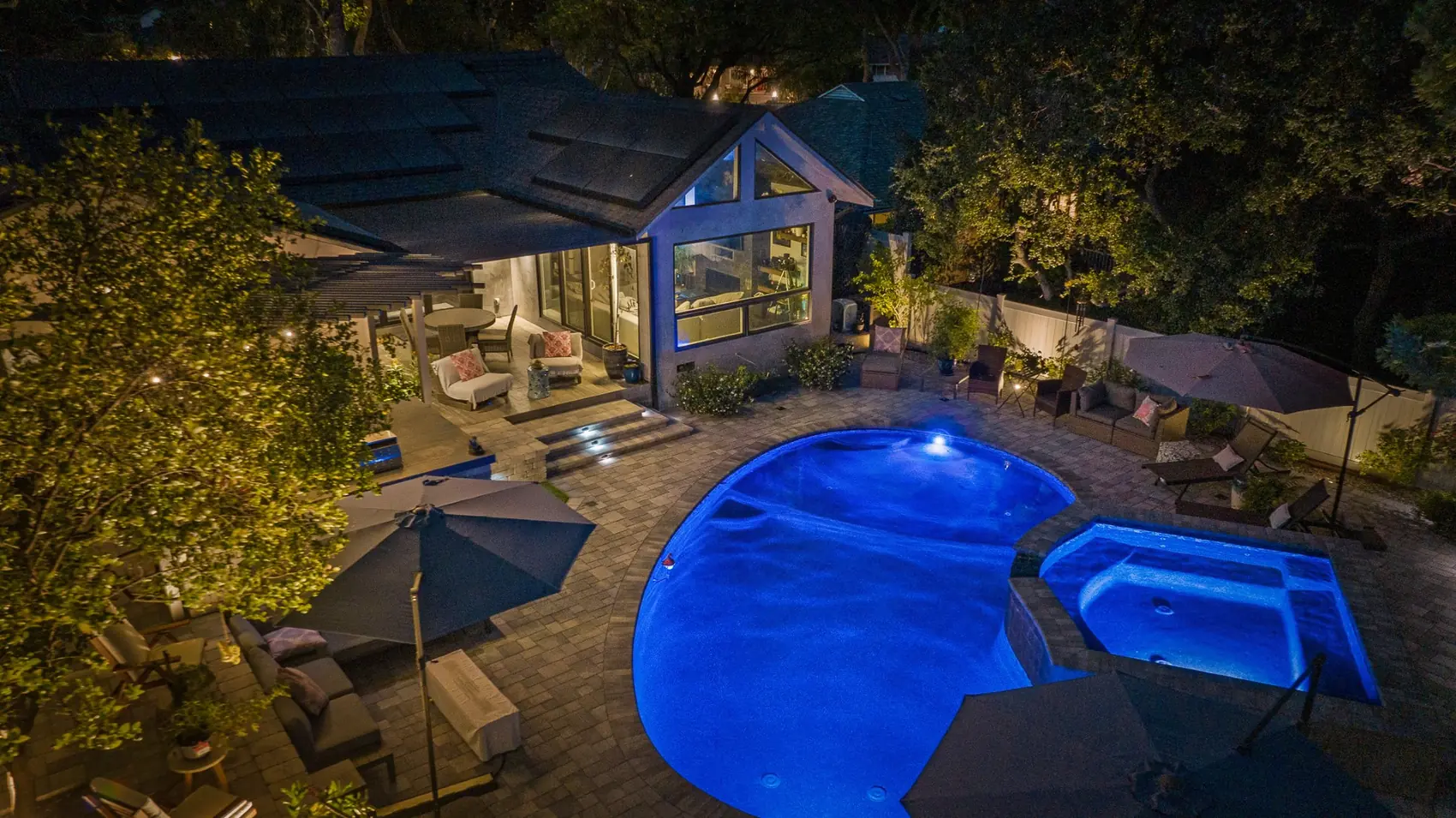 Elevated night view of a lit freeform pool and raised spa beside the patio in Pasadena