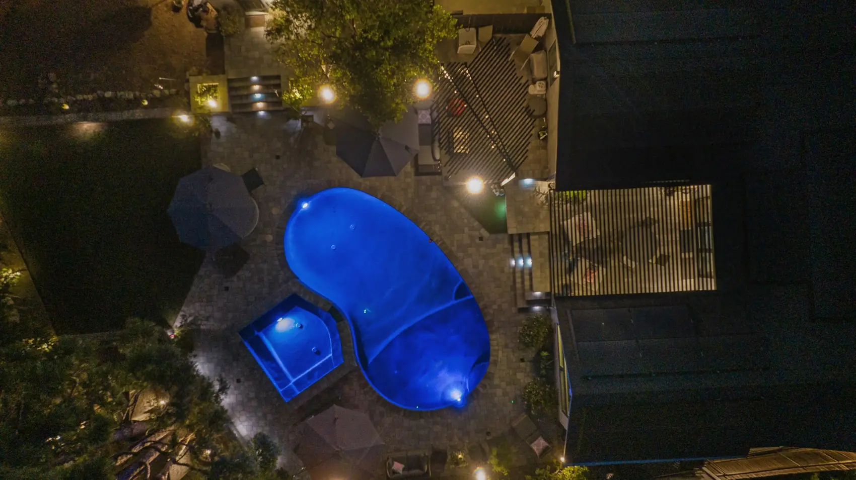 Overhead night view of a lit freeform pool and spa in Pasadena