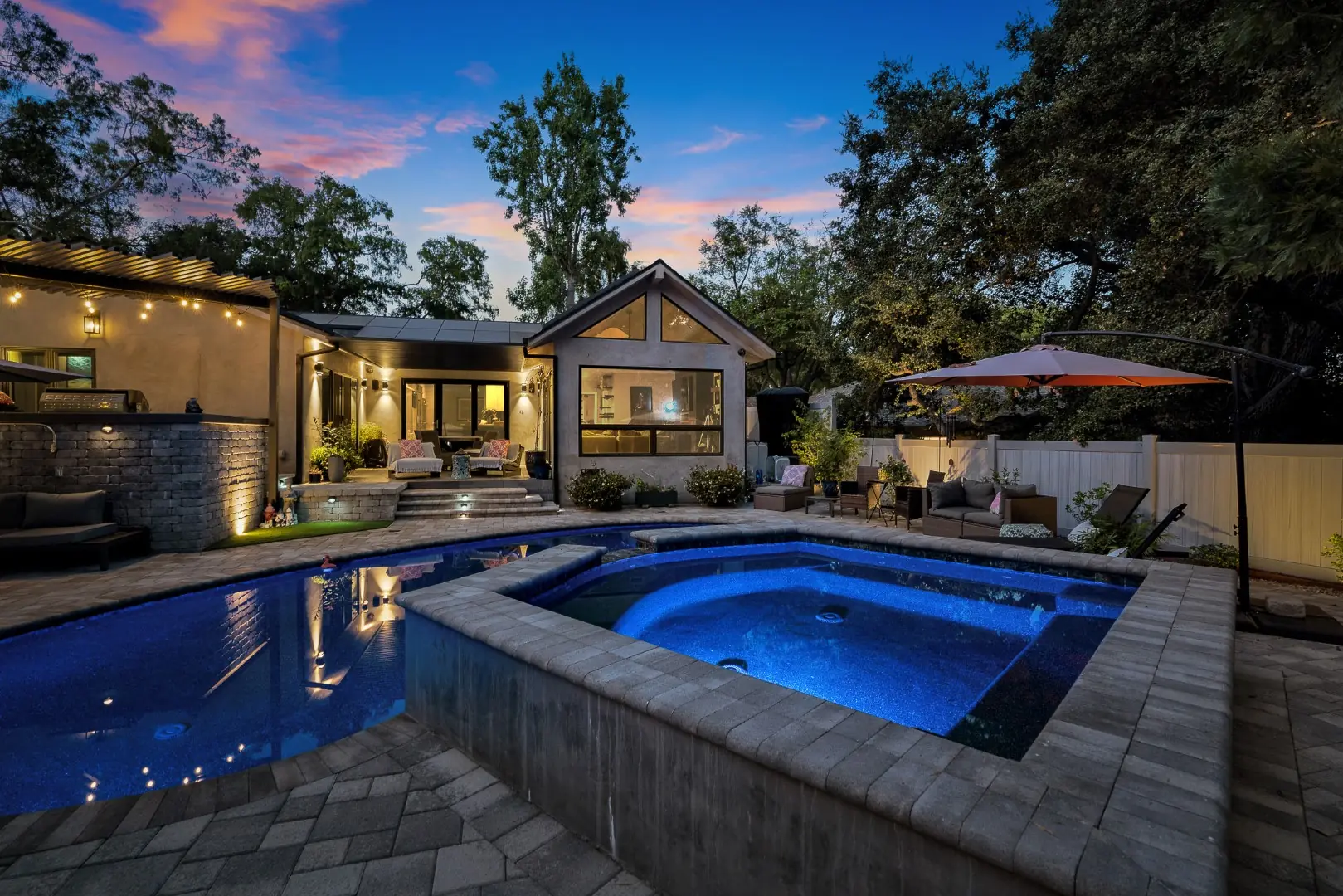 Lit raised spa and pool at night with the home and patio beyond in Pasadena