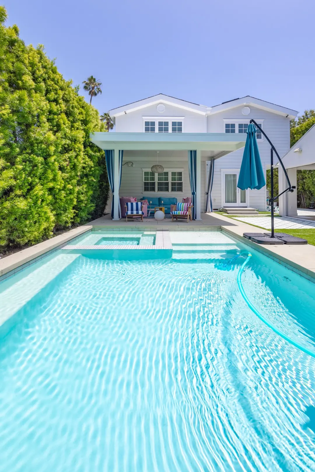 Pool leading to a white patio cover and two-story home in Studio City