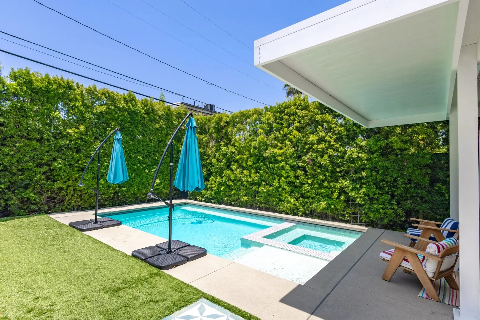 Pool and spa with cantilever umbrellas, turf, and a privacy hedge in Studio City