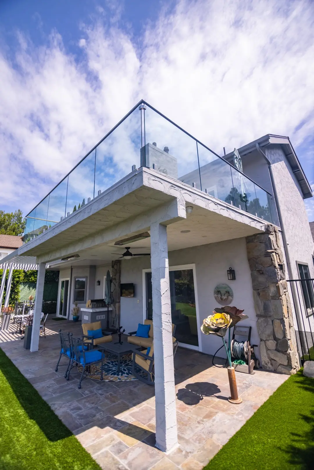 Upper balcony with a frameless glass railing above a covered patio and lawn in Beverly Glen, Los Angeles