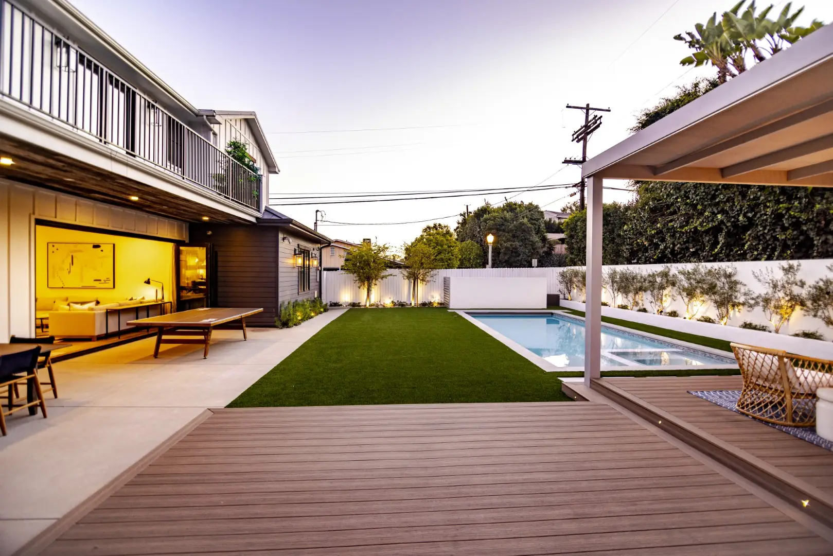 Sheens Project composite deck edge overlooking the pool, turf lawn, and lit farmhouse at dusk in Los Angeles