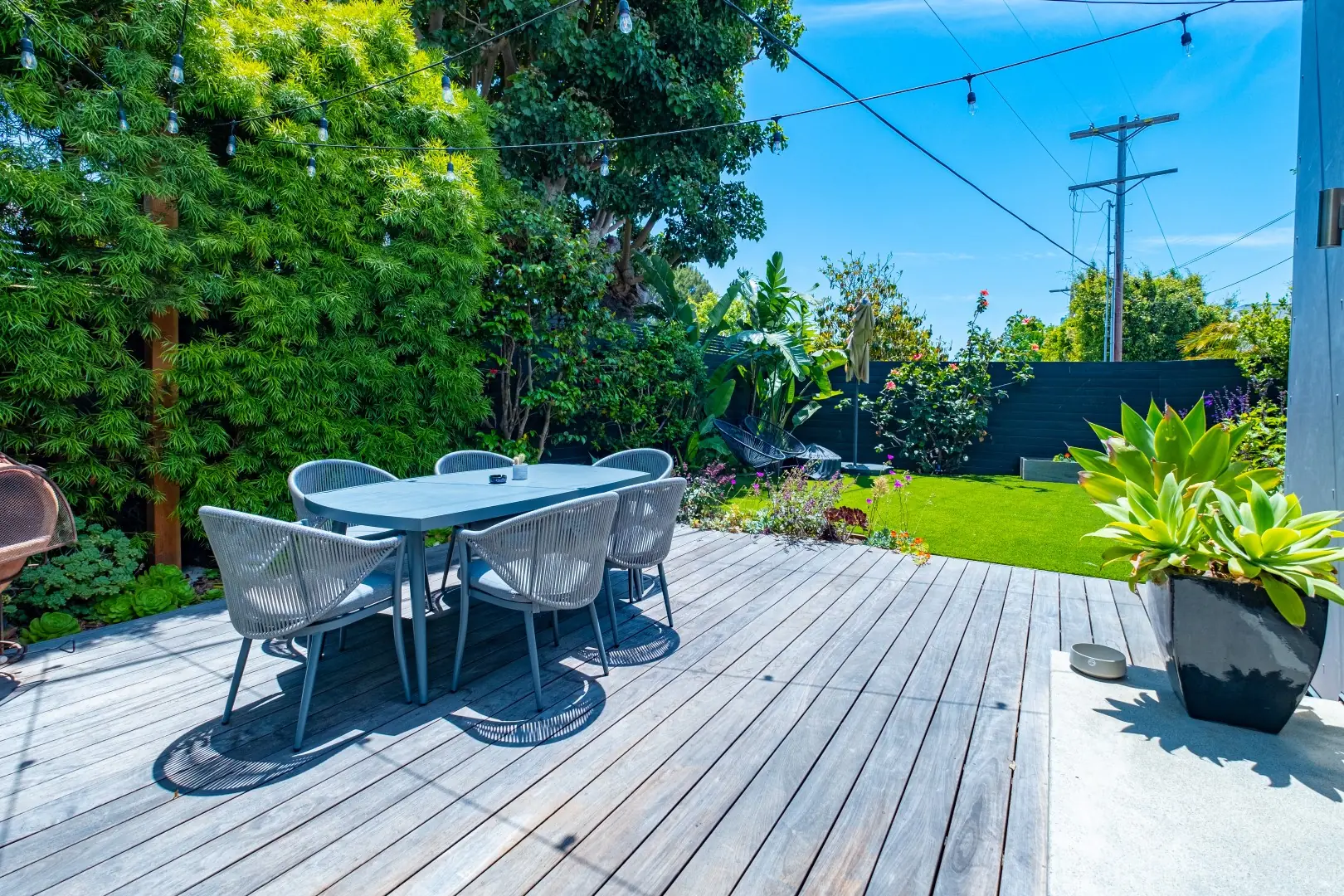 Wood deck with outdoor dining beside a landscaped backyard in Santa Monica
