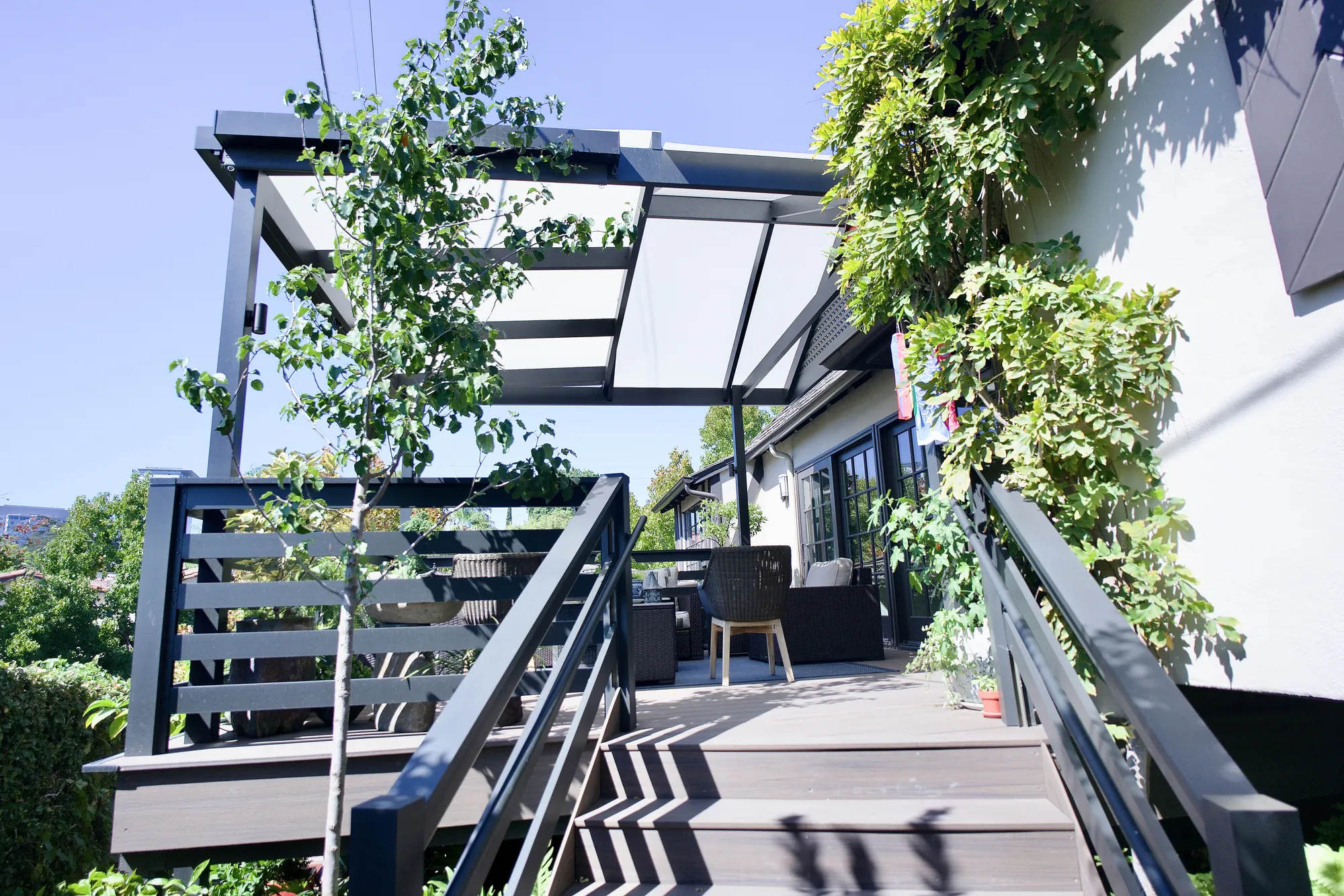 Dark-framed modern Japanese pergola with a translucent cover over a second-story composite deck and stairs in Los Angeles