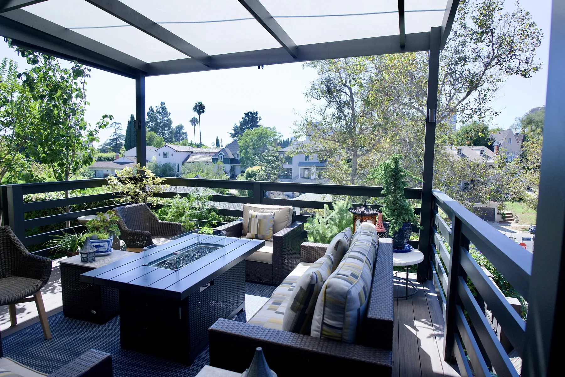 Wicker lounge and fire table under a translucent pergola cover on a second-story deck in Los Angeles