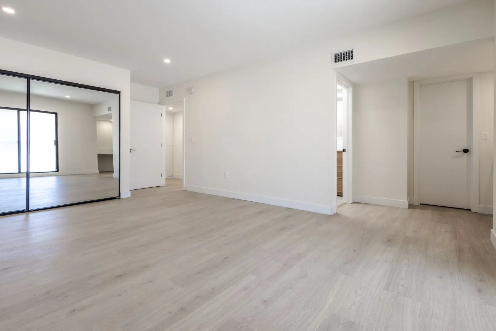Bedroom with light floors and mirrored sliding closet doors in a Northridge full-home renovation