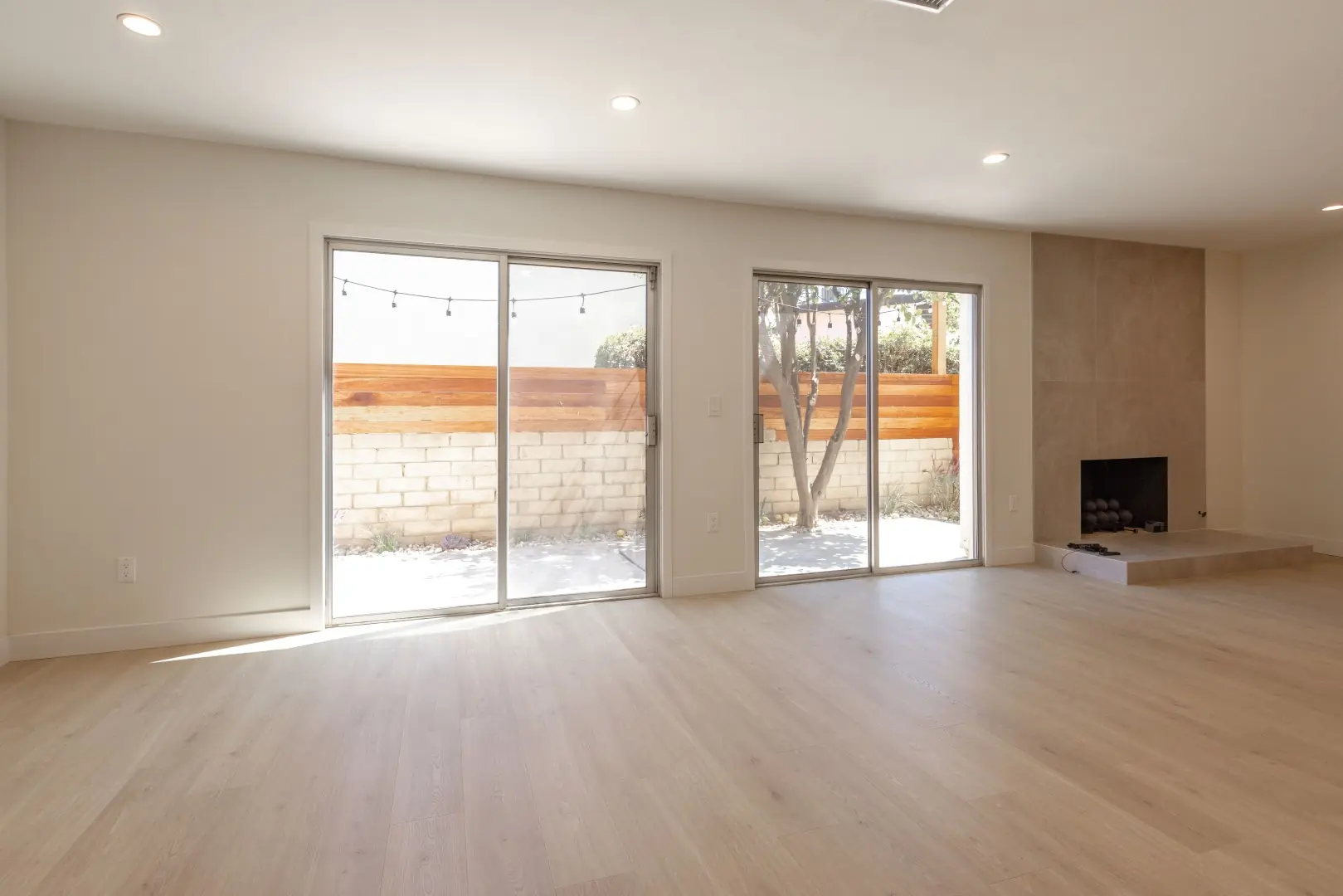 Renovated living room in Northridge with light oak-look floors, sliding glass doors, and a tiled fireplace