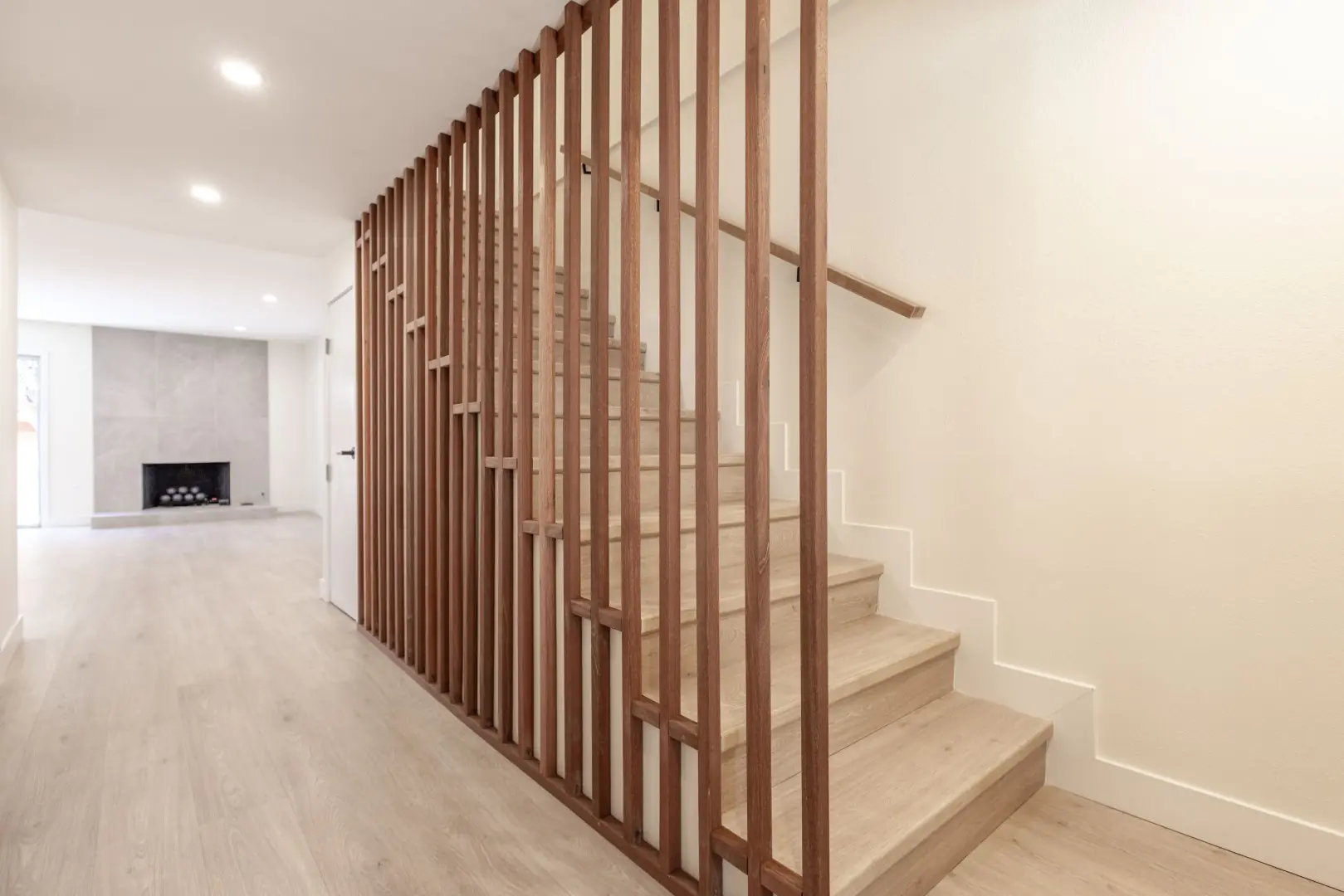 Staircase with a vertical wood slat screen and light treads in a Northridge full-home renovation