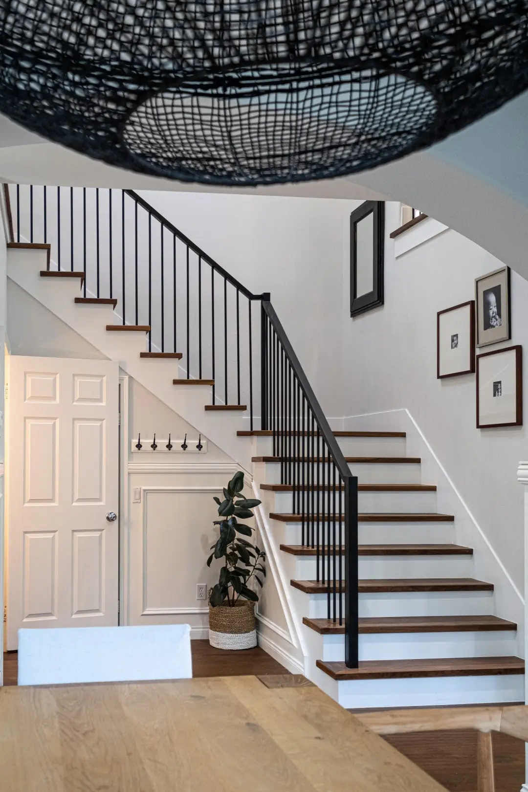 Entry staircase with black iron railings beneath a woven pendant light in a West LA full-home renovation