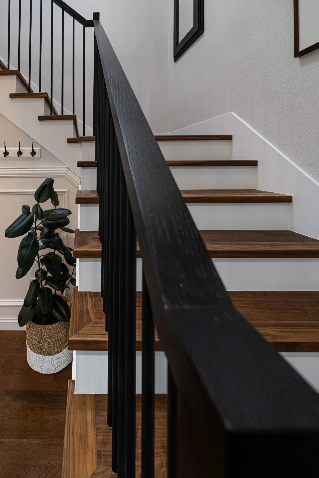 Black handrail with walnut stair treads and white risers in a West LA full-home renovation