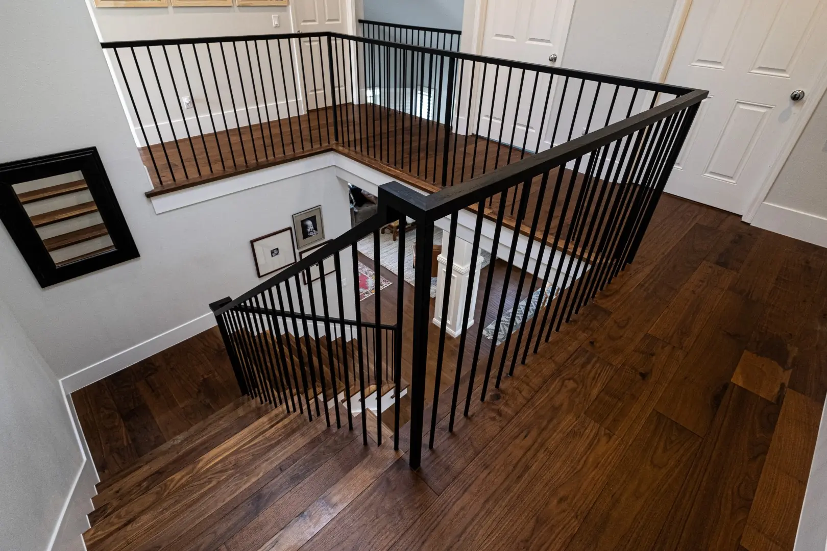 Overhead view of a renovated stair landing with black iron railings and hardwood floors in West LA