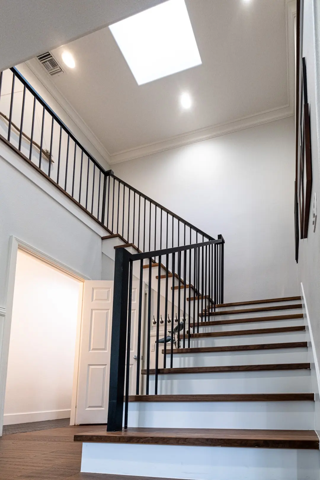 Two-story staircase under a skylight with black iron railings and wood treads in a West LA full-home renovation