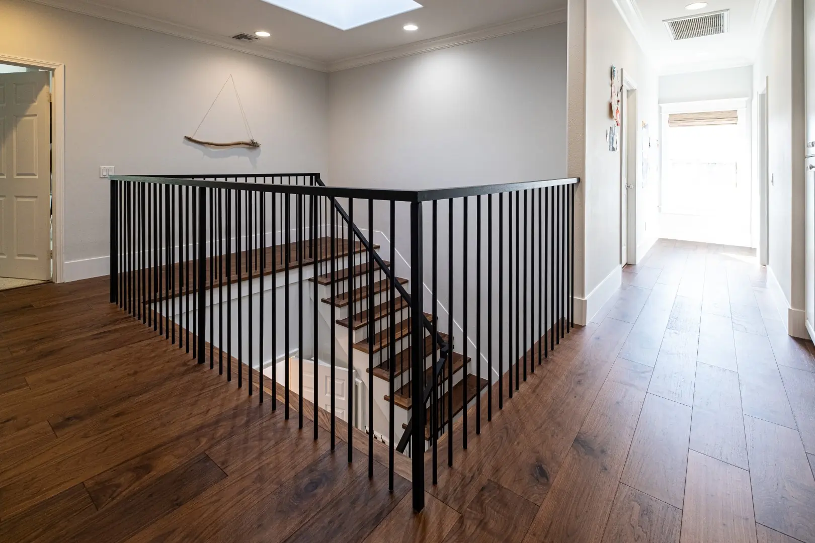 Upstairs landing with wide-plank hardwood floors, a black iron railing, and a skylight in a West LA full-home renovation