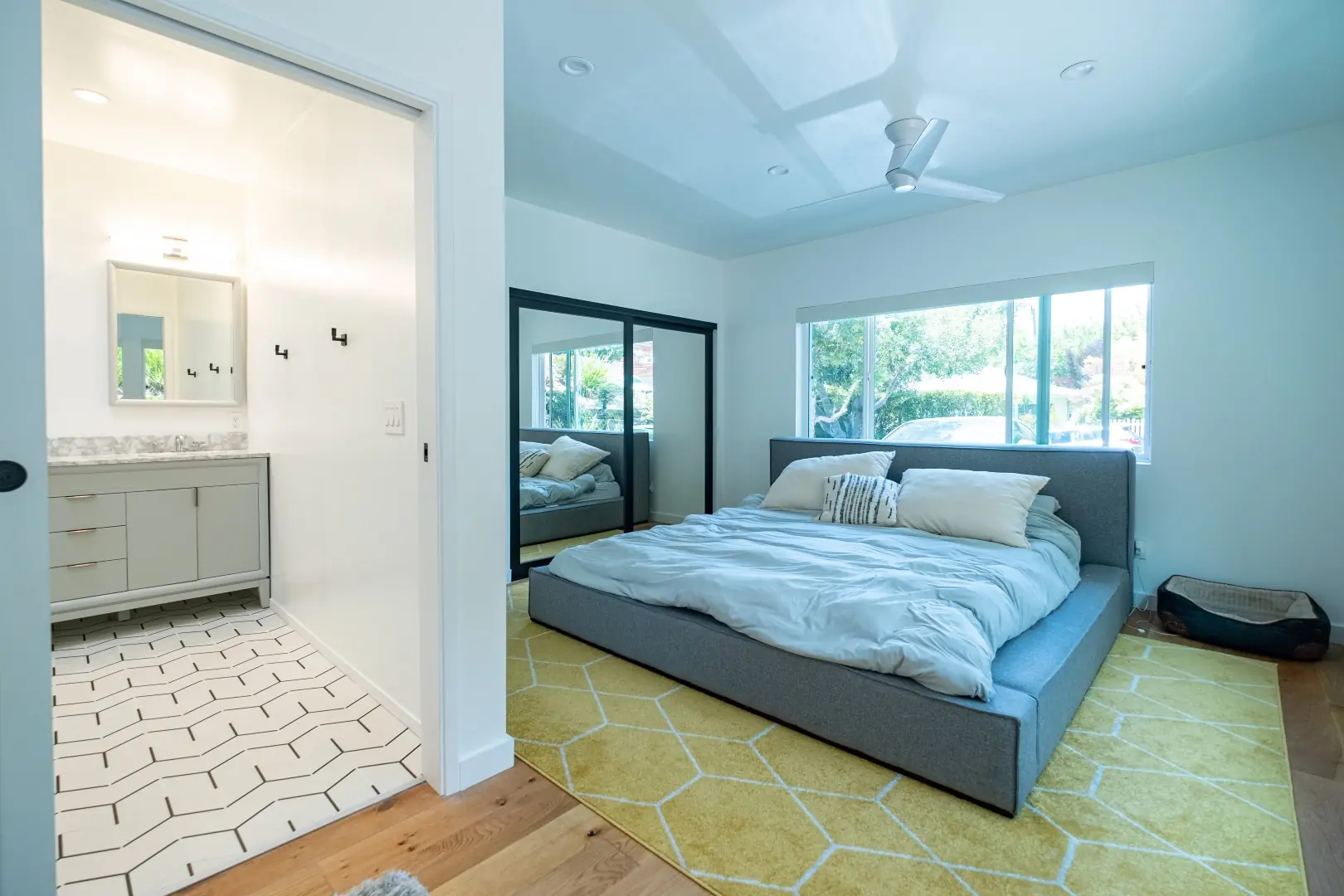 Bedroom with an en-suite bathroom, mirrored closet, and hexagon tile in a Santa Monica remodel