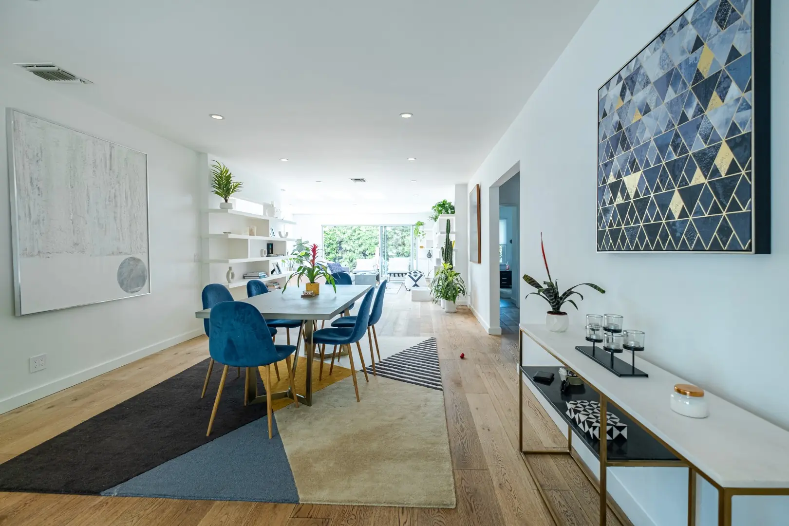 Dining area with blue velvet chairs and oak floors running through a Santa Monica home