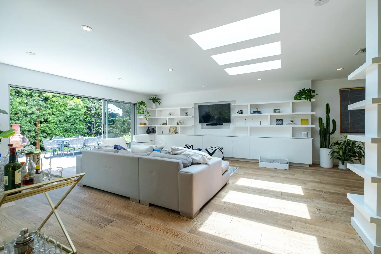 Bright living room in Santa Monica with skylights, built-in shelving, and wide-plank oak floors opening to the garden