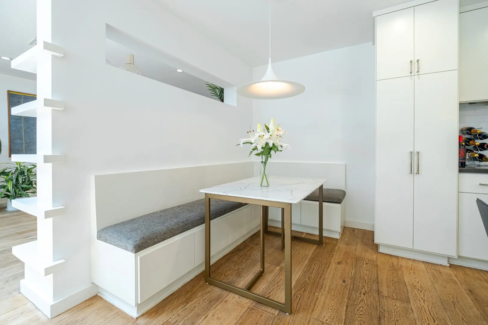 Built-in banquette and breakfast table beside tall white pantry cabinets in a Santa Monica kitchen