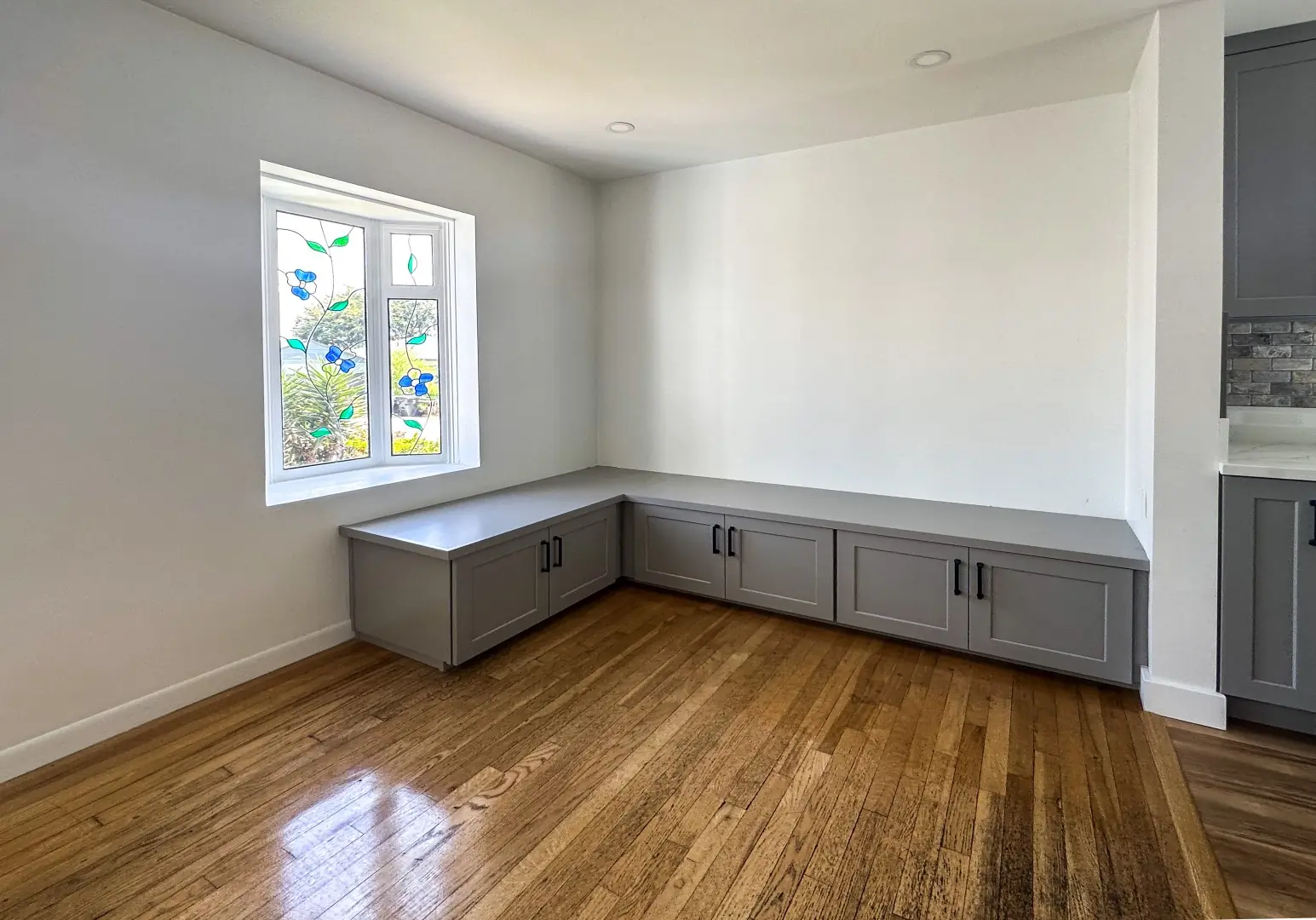 Built-in window bench with gray storage cabinets in a remodeled Santa Monica kitchen nook