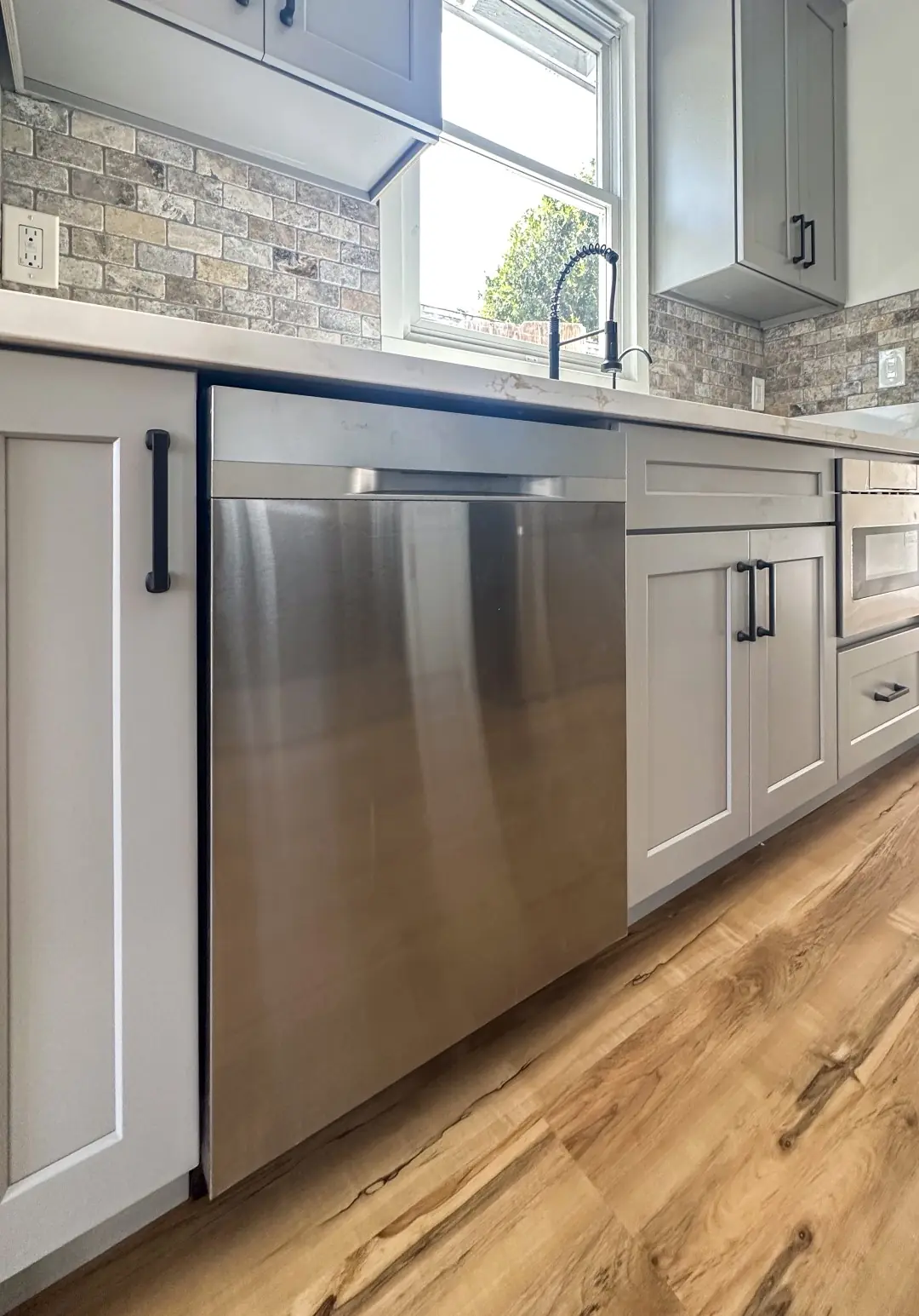 Stainless dishwasher and gray cabinets with black pulls in a Santa Monica kitchen remodel