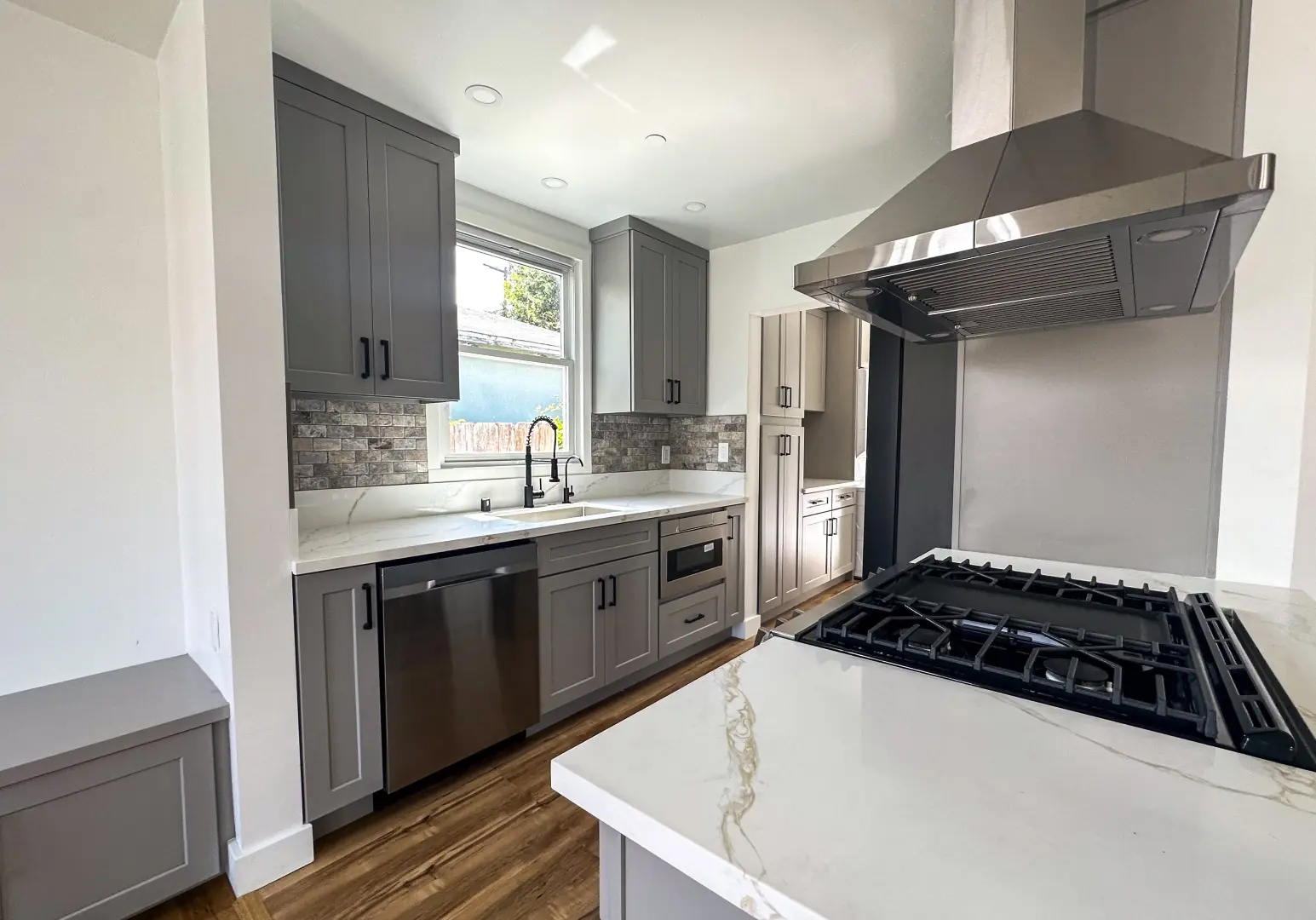 Gas range with a stainless chimney hood and veined quartz counter in a Santa Monica kitchen remodel