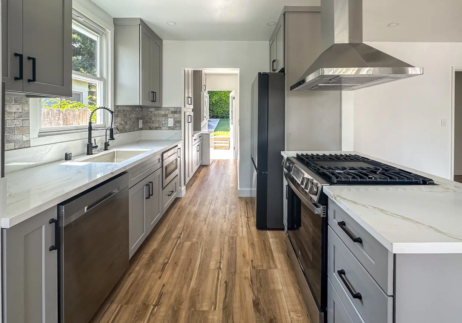 Kitchen remodel in Santa Monica with gray shaker cabinets, a stone mosaic backsplash, and white veined quartz counters