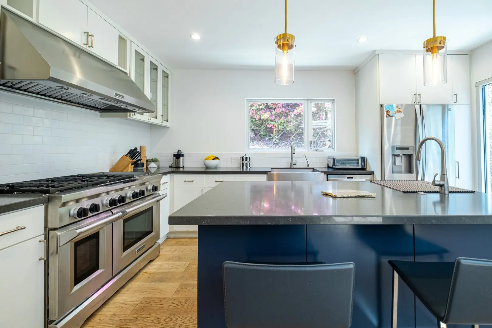 Professional range, stainless hood, and navy island with gray counters in a Santa Monica kitchen remodel