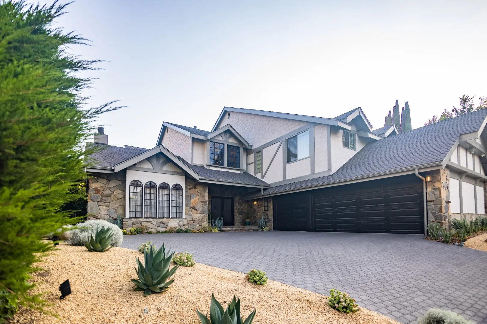Agave and succulent gravel garden beside a paver driveway at a Tudor-style home in Beverly Glen, Los Angeles