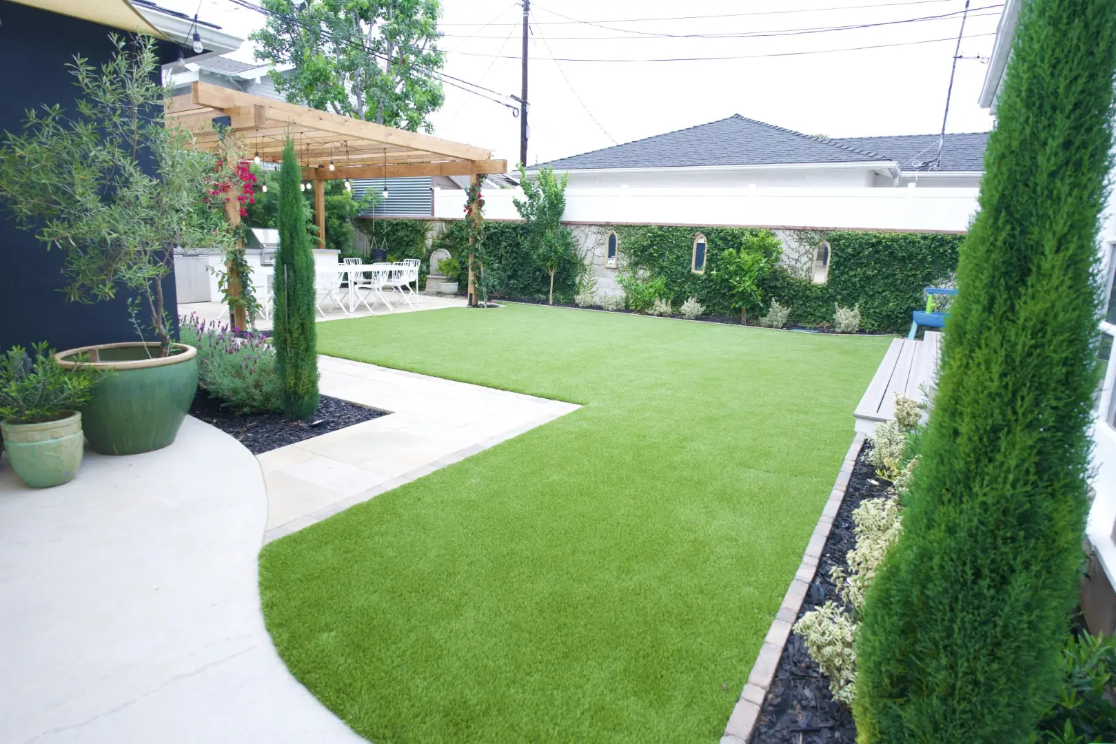 Agnew Project curved concrete path and turf lawn with planted borders and Italian cypress in a Los Angeles backyard